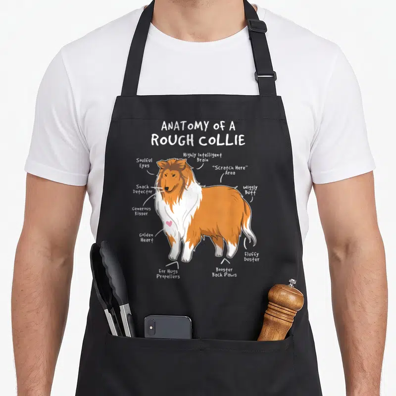 Rough dog apron - Cartoon rough collie diagram with labels like snack detector and booster back paws — shown on a black cotton canvas apron against a white background