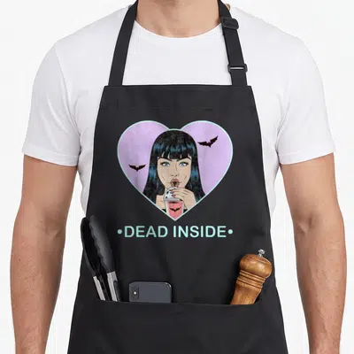 Dead goth apron - Cartoon vampire woman in pink heart with two bats and DEAD INSIDE text — shown on a black cotton canvas apron against a white background