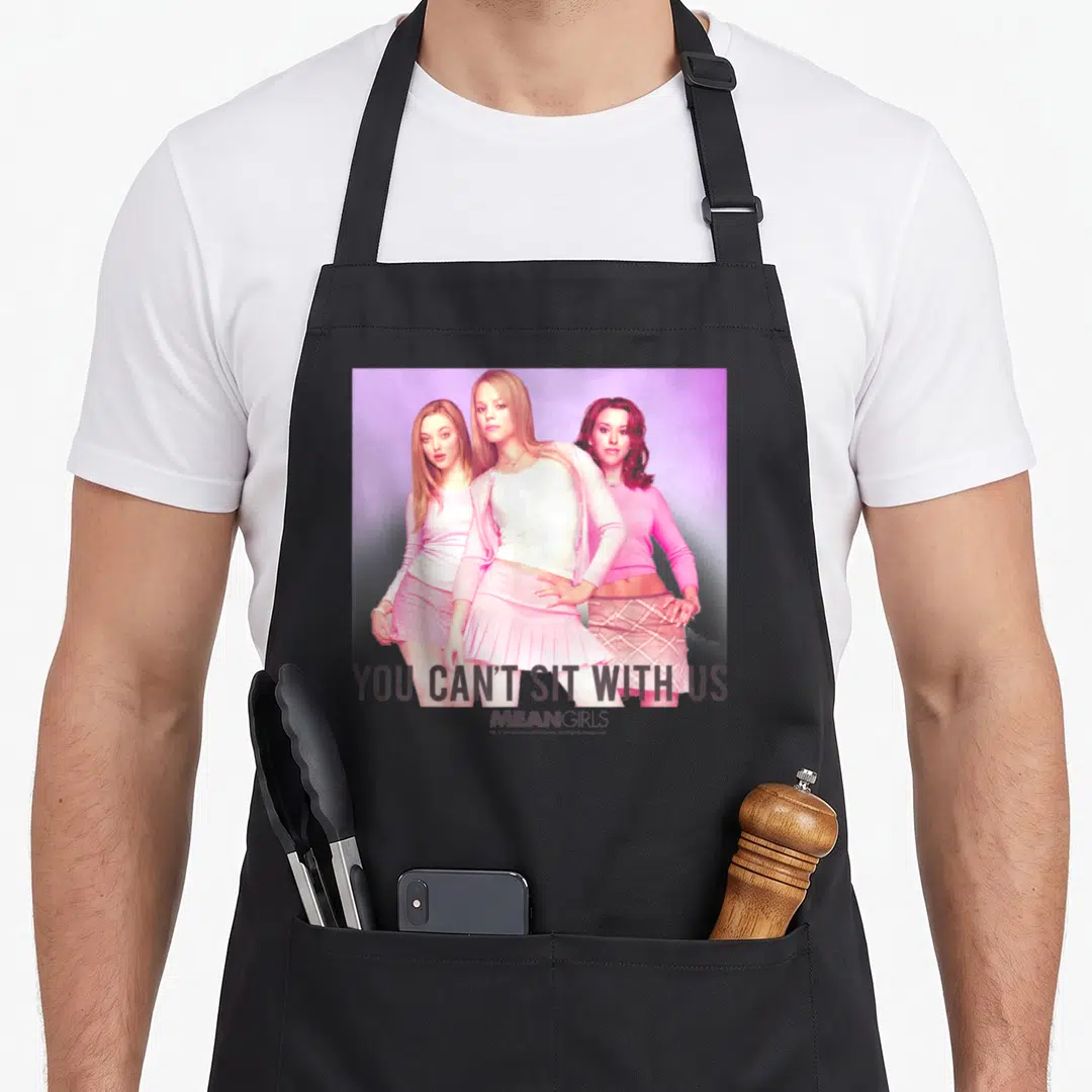 Sit us aprons - Photo of three women in pink with text YOU CAN'T SIT WITH US MEAN GIRLS — shown on a black cotton canvas apron against a white background