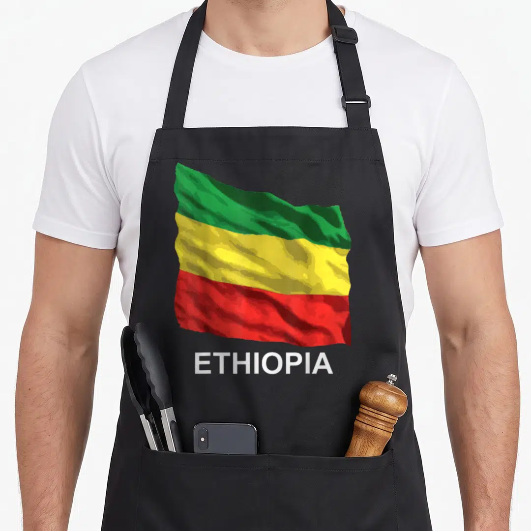 Flag ethiopian apron - Waving green yellow red flag with white ETHIOPIA text below — shown on a black cotton canvas apron against a white background