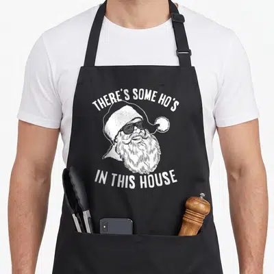 Cool novelty apron for bbq - Santa Claus head with shutter shades and white text pun — shown on a black cotton canvas apron against a white background