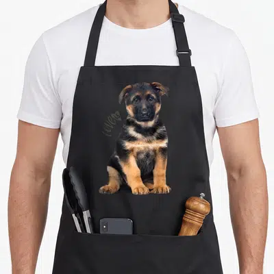 Shepard pet dog apron - German Shepherd puppy photo with love is script text in black tan grey — shown on a black cotton canvas apron against a white background
