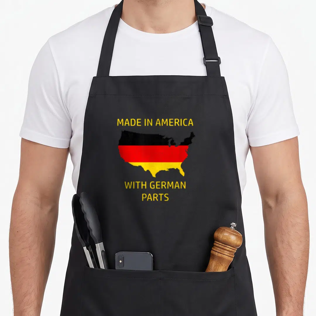 Part german apron - Distressed USA map with German flag colors and text MADE IN AMERICA WITH GERMAN PARTS — shown on a black cotton canvas apron against a white background