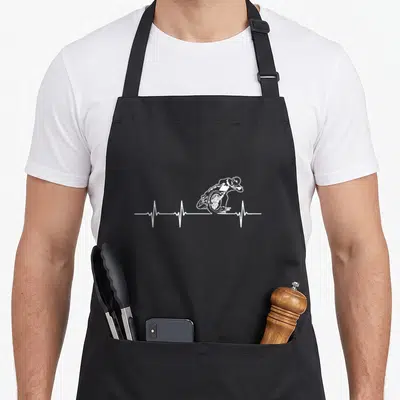 Flat motorcycle aprons - White line-art motorcyclist merged with a horizontal heartbeat EKG line on grey background — shown on a black cotton canvas apron against a white background