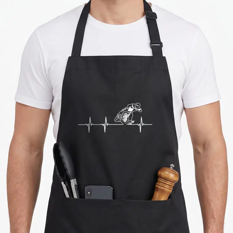 Flat motorcycle aprons - White line-art motorcyclist merged with a horizontal heartbeat EKG line on grey background — shown on a black cotton canvas apron against a white background