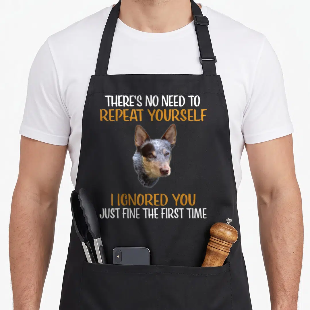 Blue dog kitchen apron - Australian Cattle Dog photo between white and orange sarcastic text on grey background — shown on a black cotton canvas apron against a white background