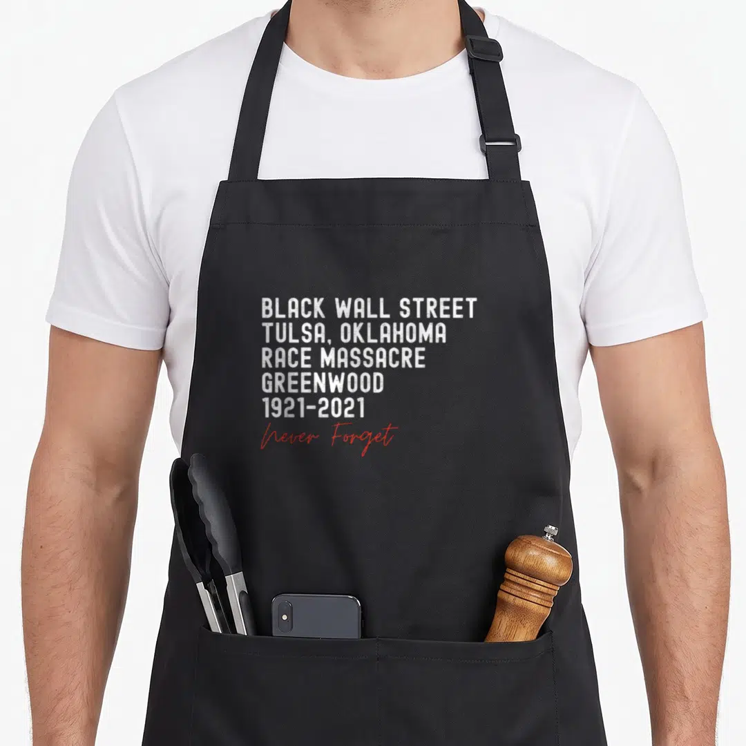 Race tulsa apron - Stacked white text reading Black Wall Street Tulsa Race Massacre Greenwood 1921-2021 with red Never — shown on a black cotton canvas apron against a white background