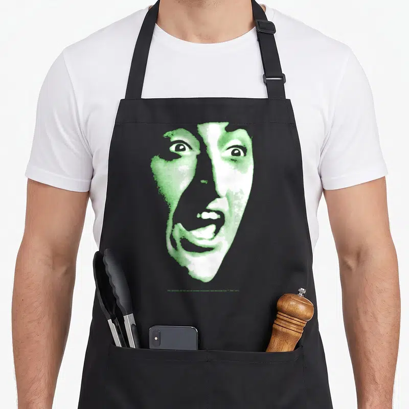 Wizard witch apron - Stylized green and white face print on apron with two front pockets — shown on a black cotton canvas apron against a white background