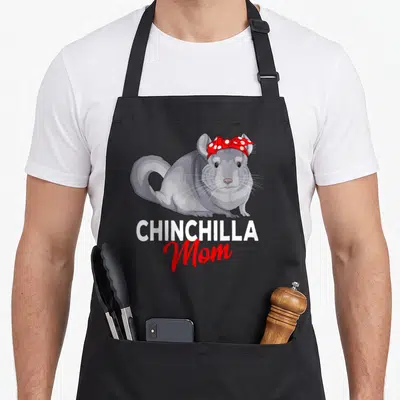 Funny chinchilla mother's day aprons - Cartoon grey chinchilla with red bow above white and red CHINCHILLA Mom text — shown on a black cotton canvas apron against a white background
