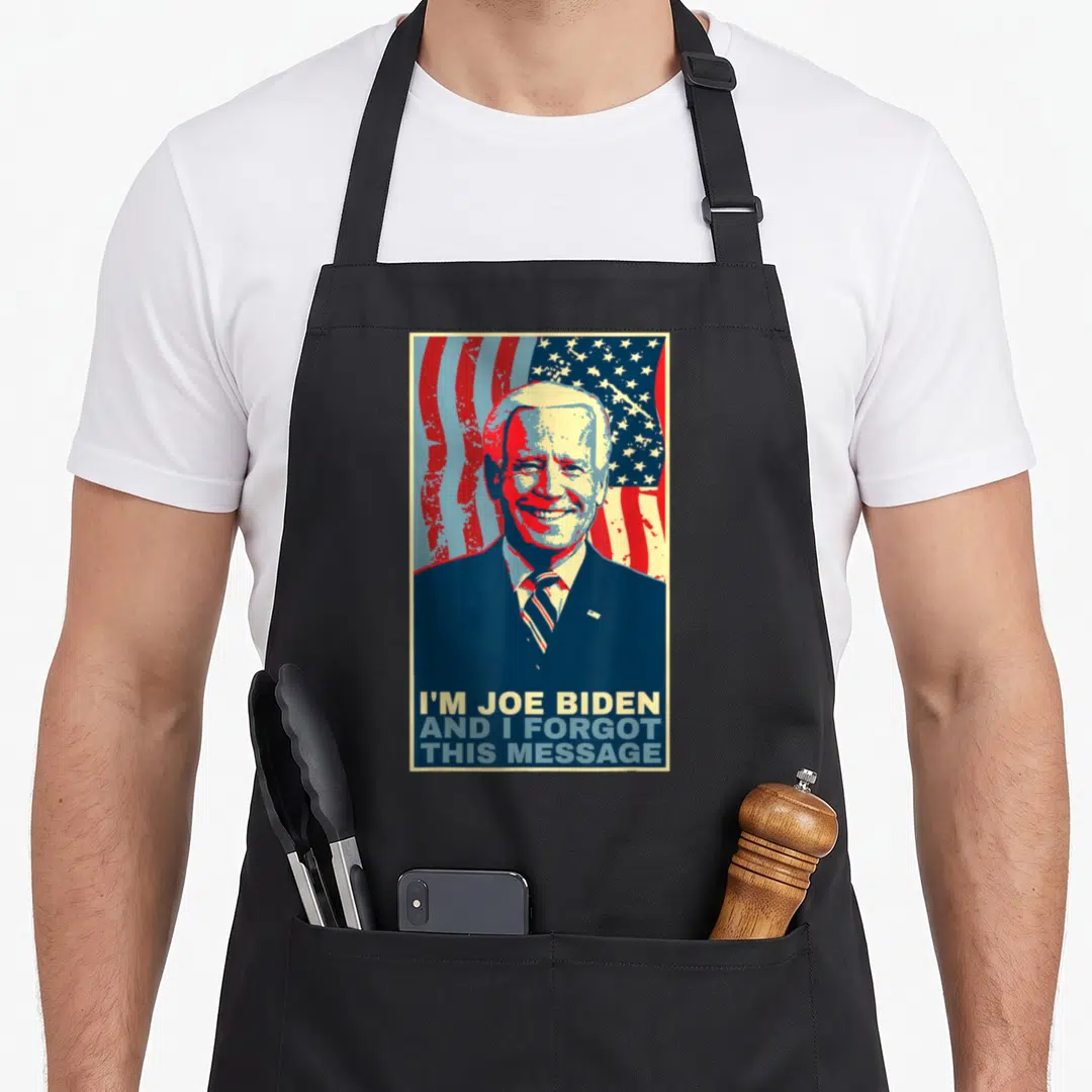 Joe meme apron - Retro poster style portrait of Joe Biden with red white and blue flag and three lines of text reading — shown on a black cotton canvas apron against a white background