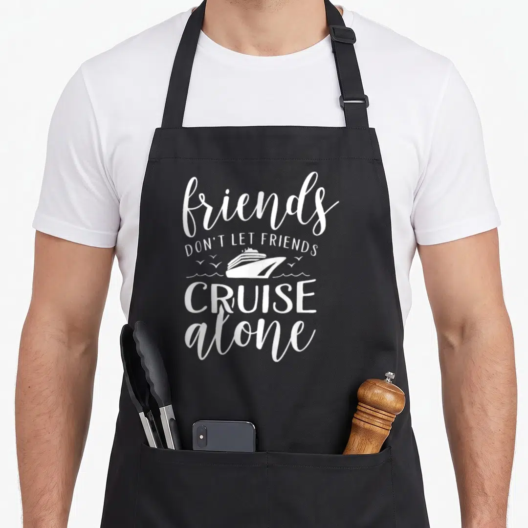 Alone friends apron - White typography reading friends don't let friends cruise alone with ship and wave graphic — shown on a black cotton canvas apron against a white background