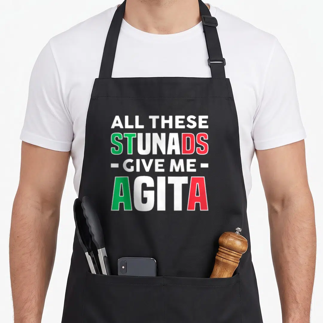 These italian apron - Stacked text All These Stunads Give Me Agita in white green and red block letters — shown on a black cotton canvas apron against a white background