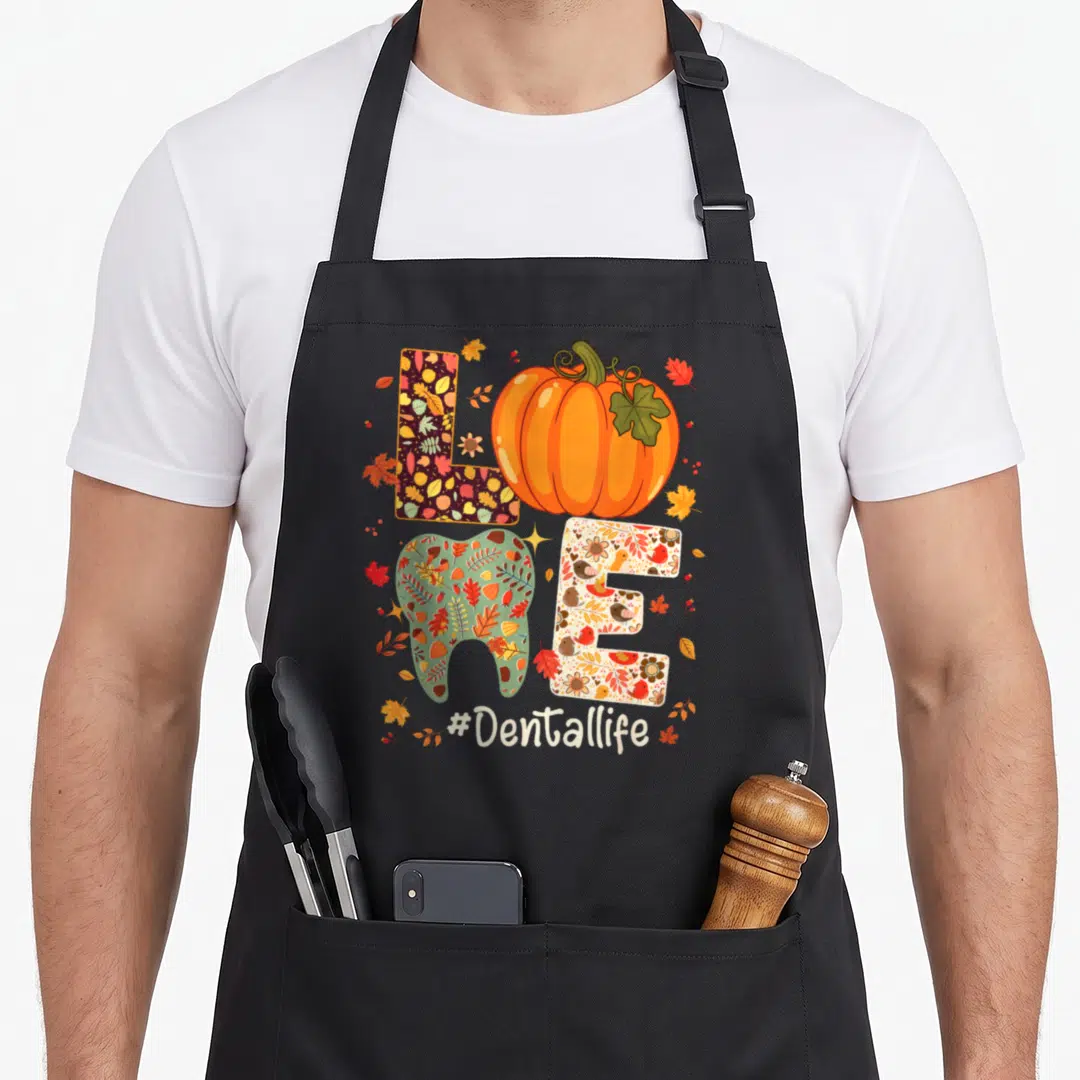 Dental thanksgiving apron - LOVE spelled with patterned L, pumpkin O, tooth V, beige E, and #Dentallife hashtag below — shown on a black cotton canvas apron against a white background