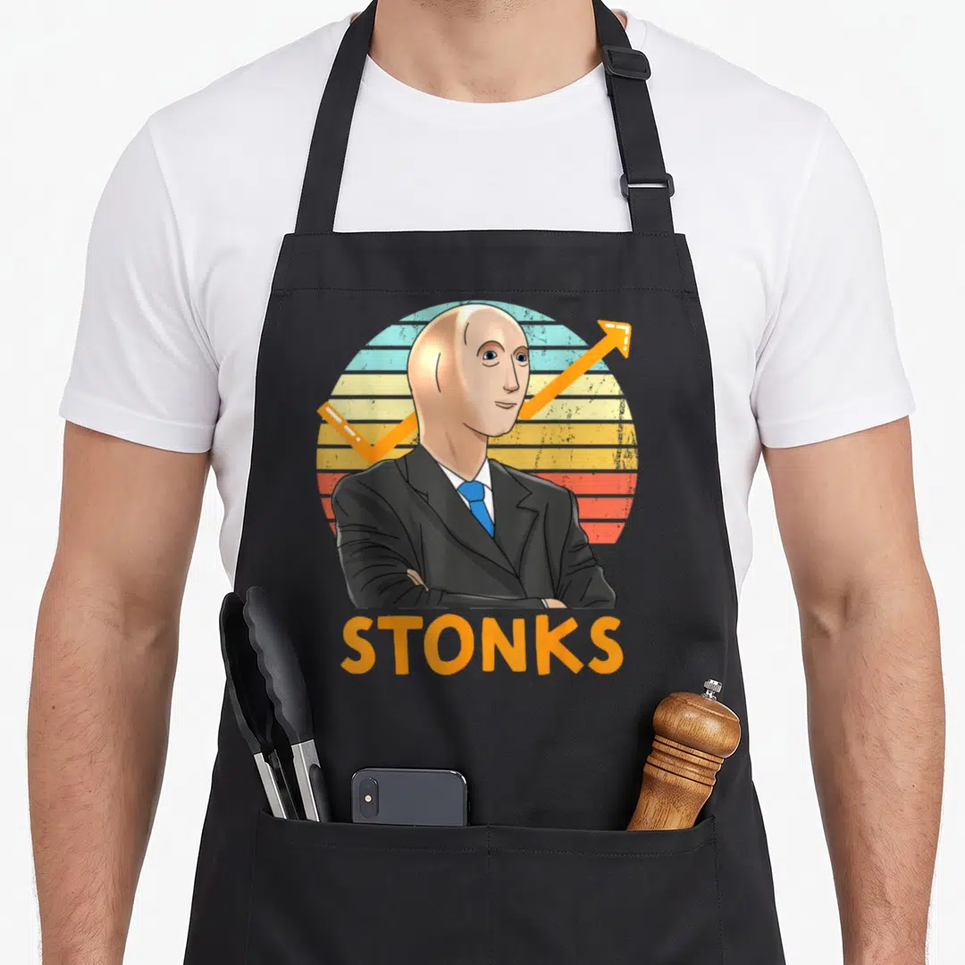 Stonk stock aprons - Cartoon man in suit with blue tie and orange arrow above STONKS text on striped background — shown on a black cotton canvas apron against a white background