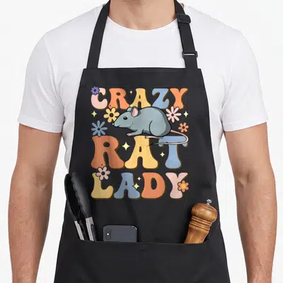 Rat groovy pet apron - Cartoon grey rat over vertical CRAZY RAT LADY text with colorful flowers and stars — shown on a black cotton canvas apron against a white background