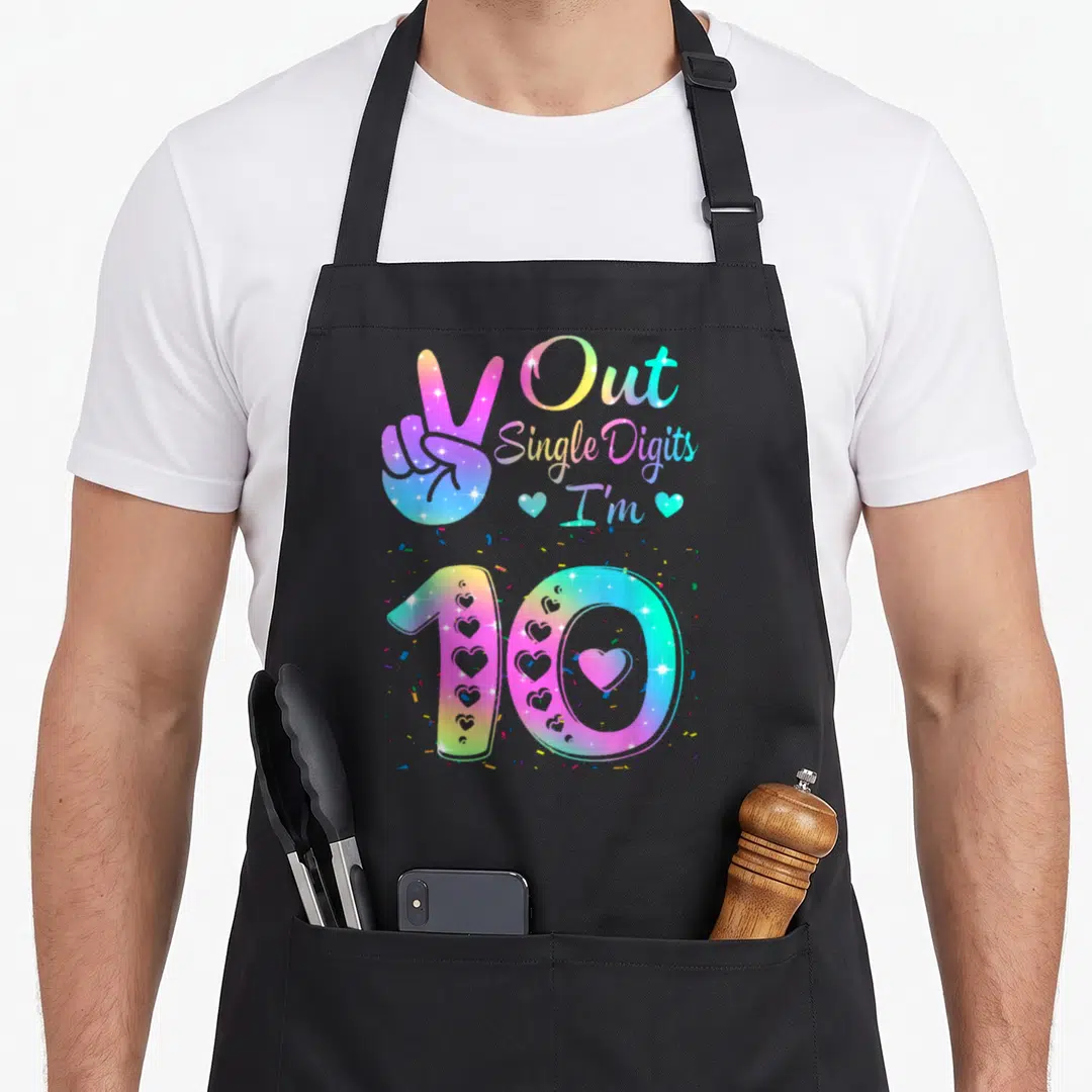Digit tie-dye apron - Peace sign hand and number 10 with confetti and hearts in rainbow gradient colors — shown on a black cotton canvas apron against a white background