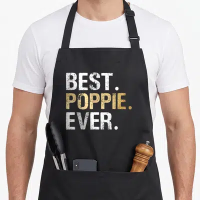 Poppie goddaughter apron - Stacked white and gold text reading BEST. POPPIE. EVER — shown on a black cotton canvas apron against a white background