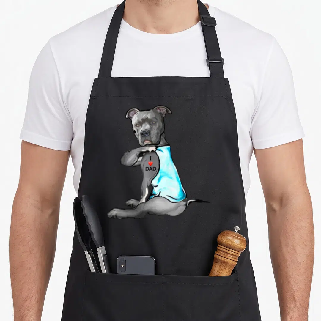 Dog tattoo aprons - Cartoon grey pitbull in blue tank top with I heart DAD text and red heart — shown on a black cotton canvas apron against a white background