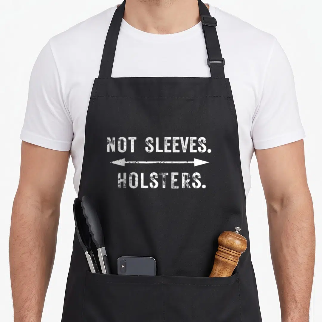 Gym gun apron - White distressed text reading NOT SLEEVES HOLSTERS separated by double arrow — shown on a black cotton canvas apron against a white background
