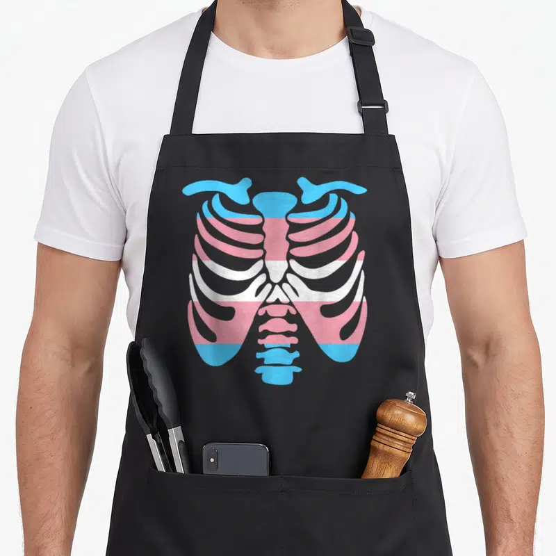 Transgender ribs apron - Ribcage outline filled with horizontal blue pink and white transgender pride flag stripes — shown on a black cotton canvas apron against a white background