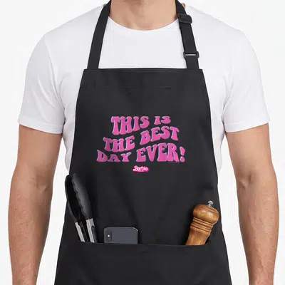 Funny movie general apron - Pink wavy text THIS IS THE BEST DAY EVER! with light blue outline and small Barbie logo — shown on a black cotton canvas apron against a white background