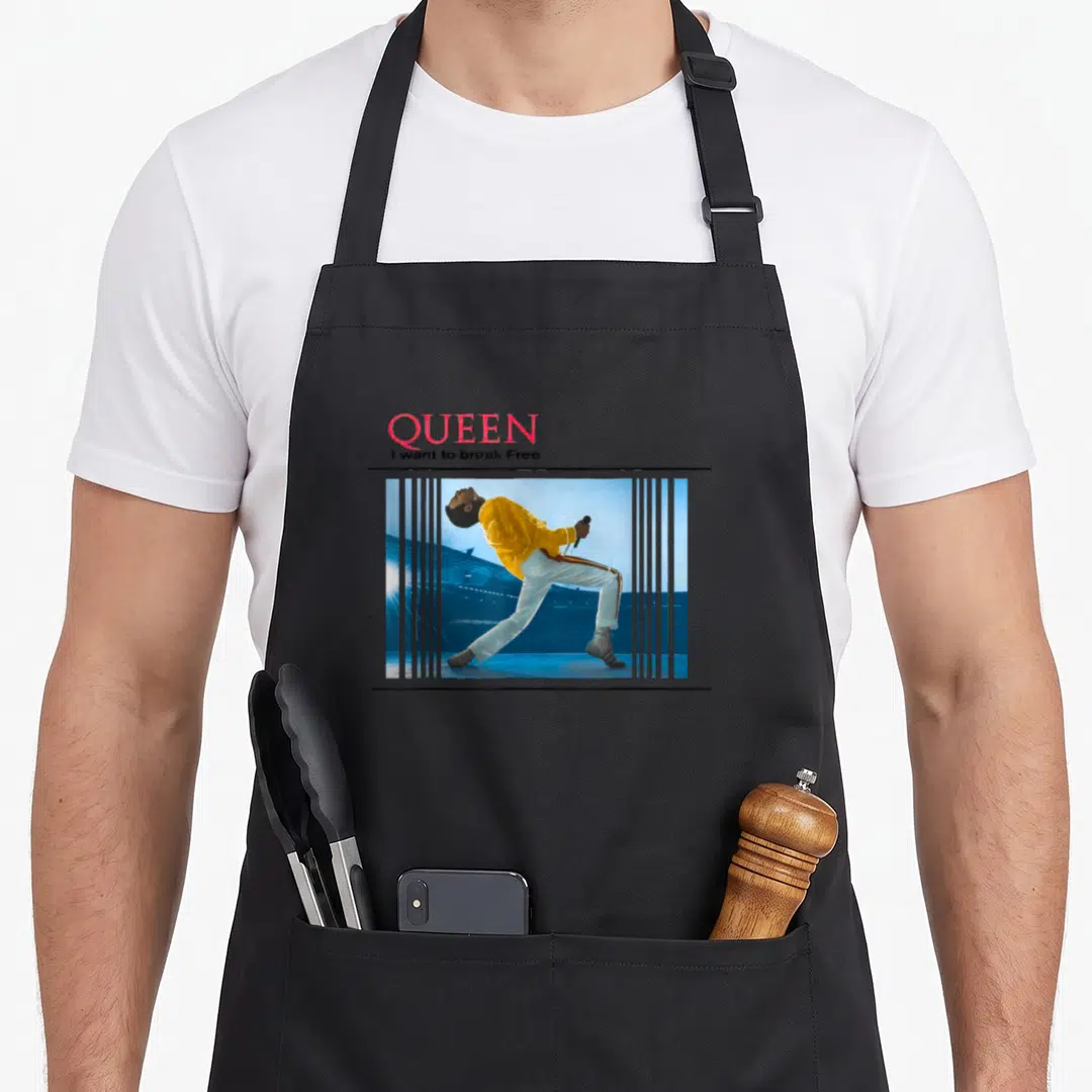 Break queen apron - Stacked QUEEN text above striped photo of singer in yellow leaning back with microphone — shown on a black cotton canvas apron against a white background