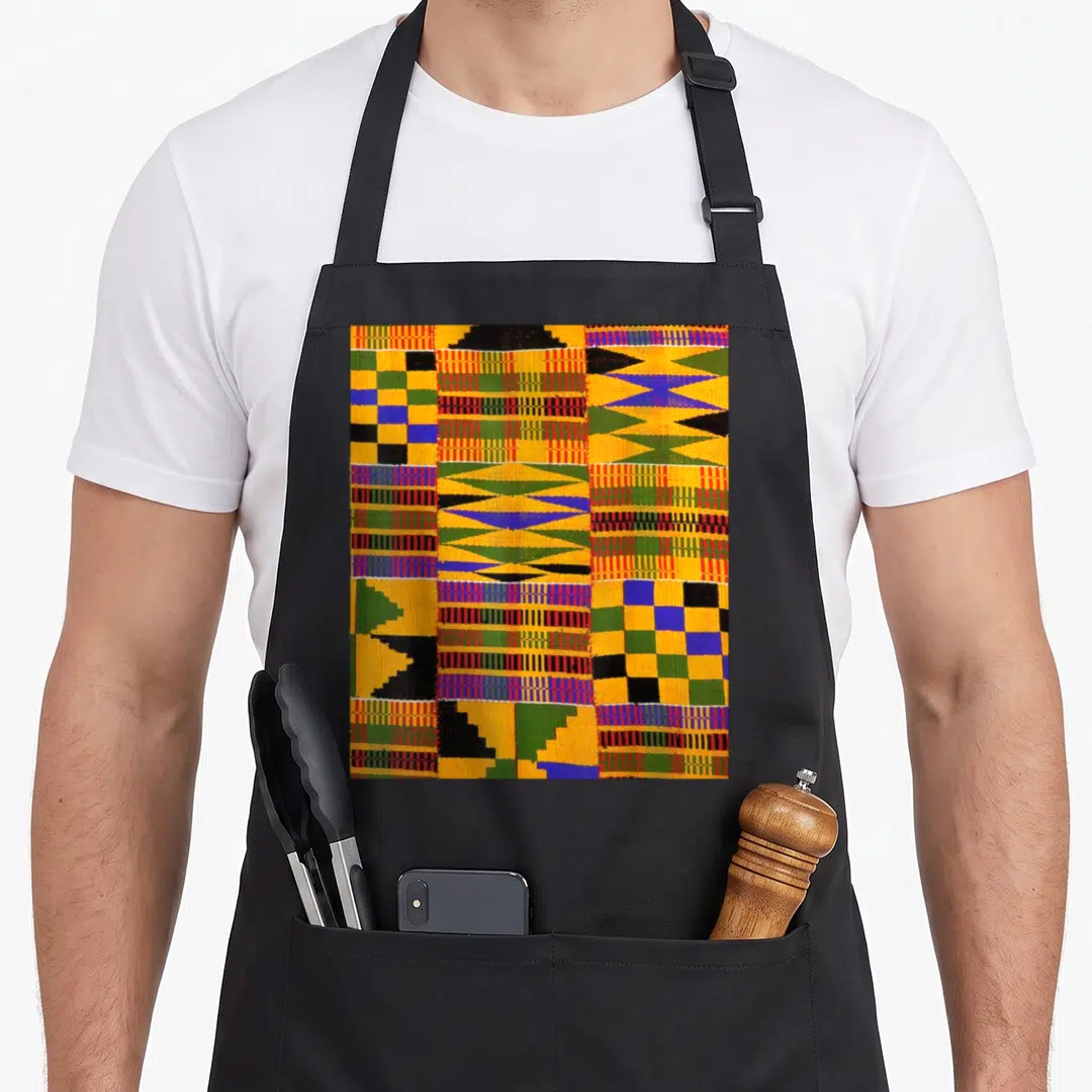 African cloth aprons - Geometric Kente textile pattern in yellow orange green blue and black with woven texture details — shown on a black cotton canvas apron against a white background