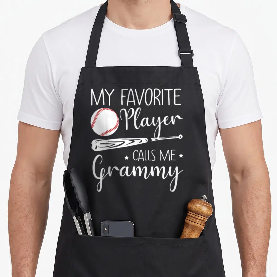 Baseball grammy apron - My Favorite Player Calls Me Grammy text with white baseball and bat on black apron — shown on a black cotton canvas apron against a white background