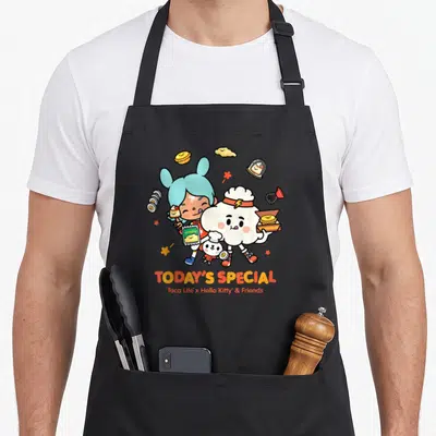 Toca special aprons - Two cartoon characters holding food items with TODAY'S SPECIAL text below — shown on a black cotton canvas apron against a white background