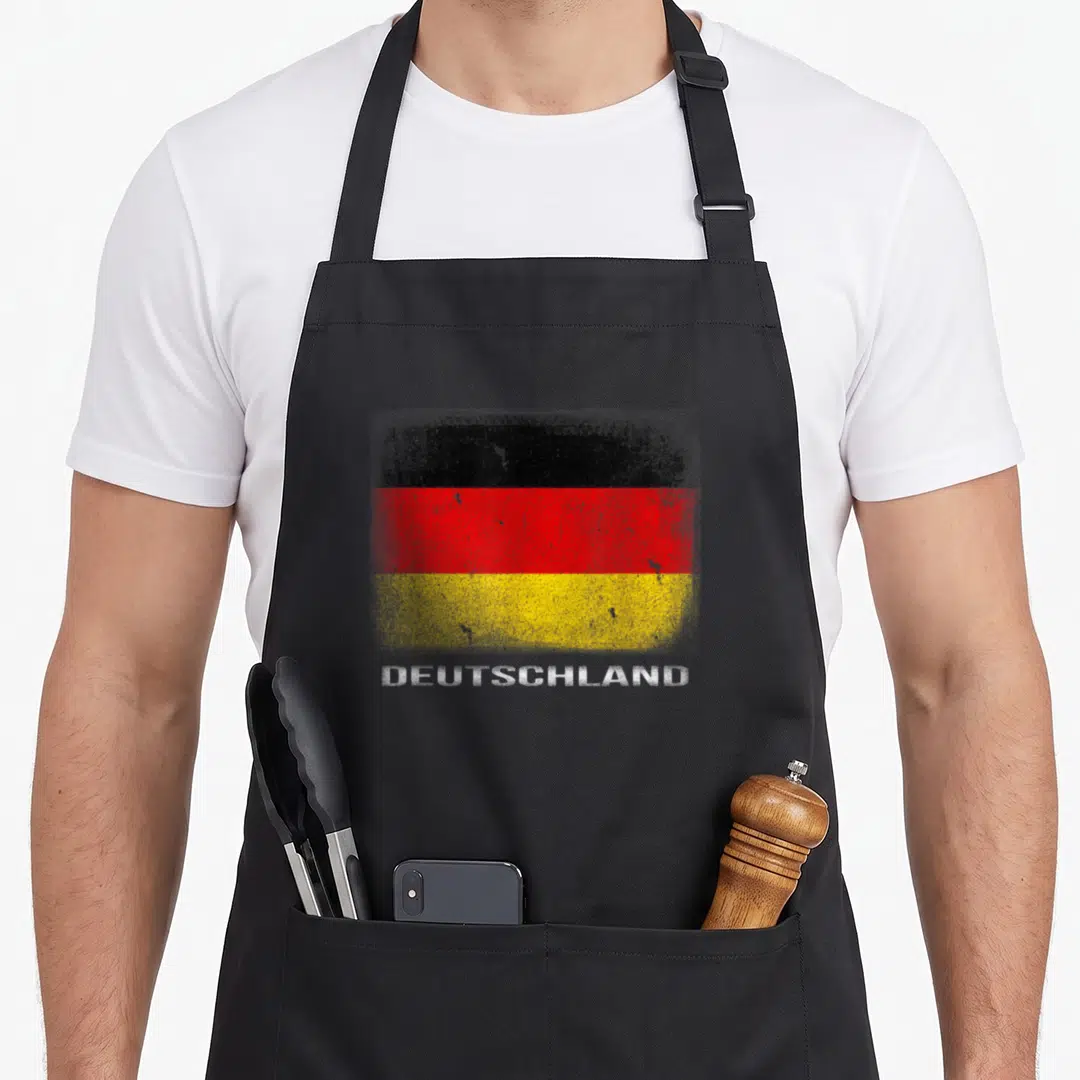 Souvenir german apron - Distressed German flag stripes above white DEUTSCHLAND text on apron front panel — shown on a black cotton canvas apron against a white background