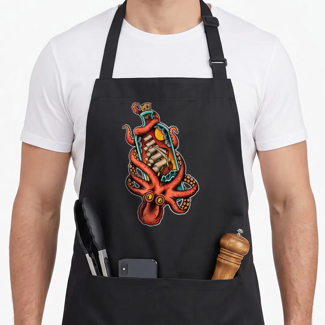 Octopus tattoo apron - Red octopus wrapped around glass bottle containing sailing ship in cartoon tattoo style — shown on a black cotton canvas apron against a white background