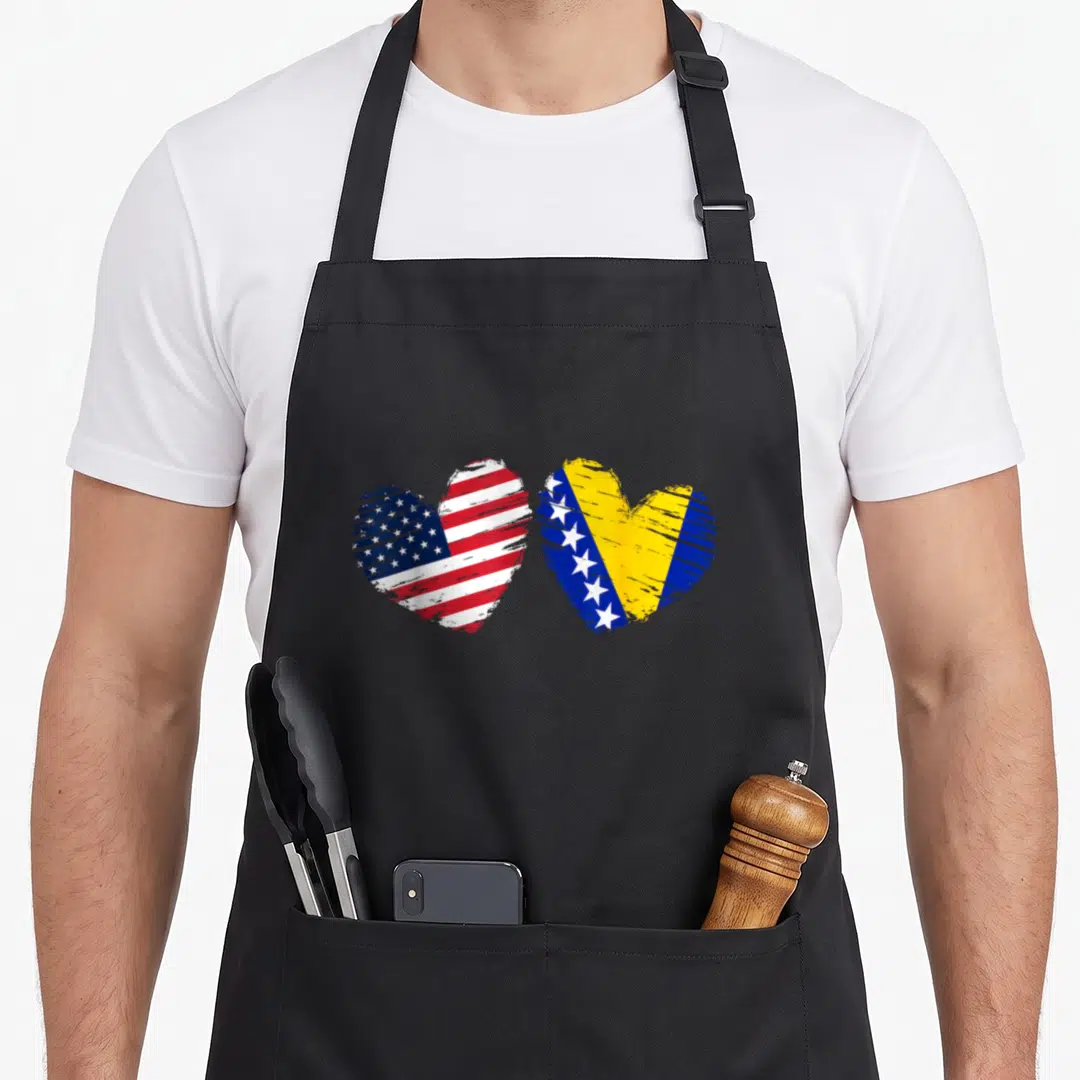 Herzegovina american flag apron - Two distressed hearts filled with USA and Bosnia Herzegovina flag patterns in red — shown on a black cotton canvas apron against a white background