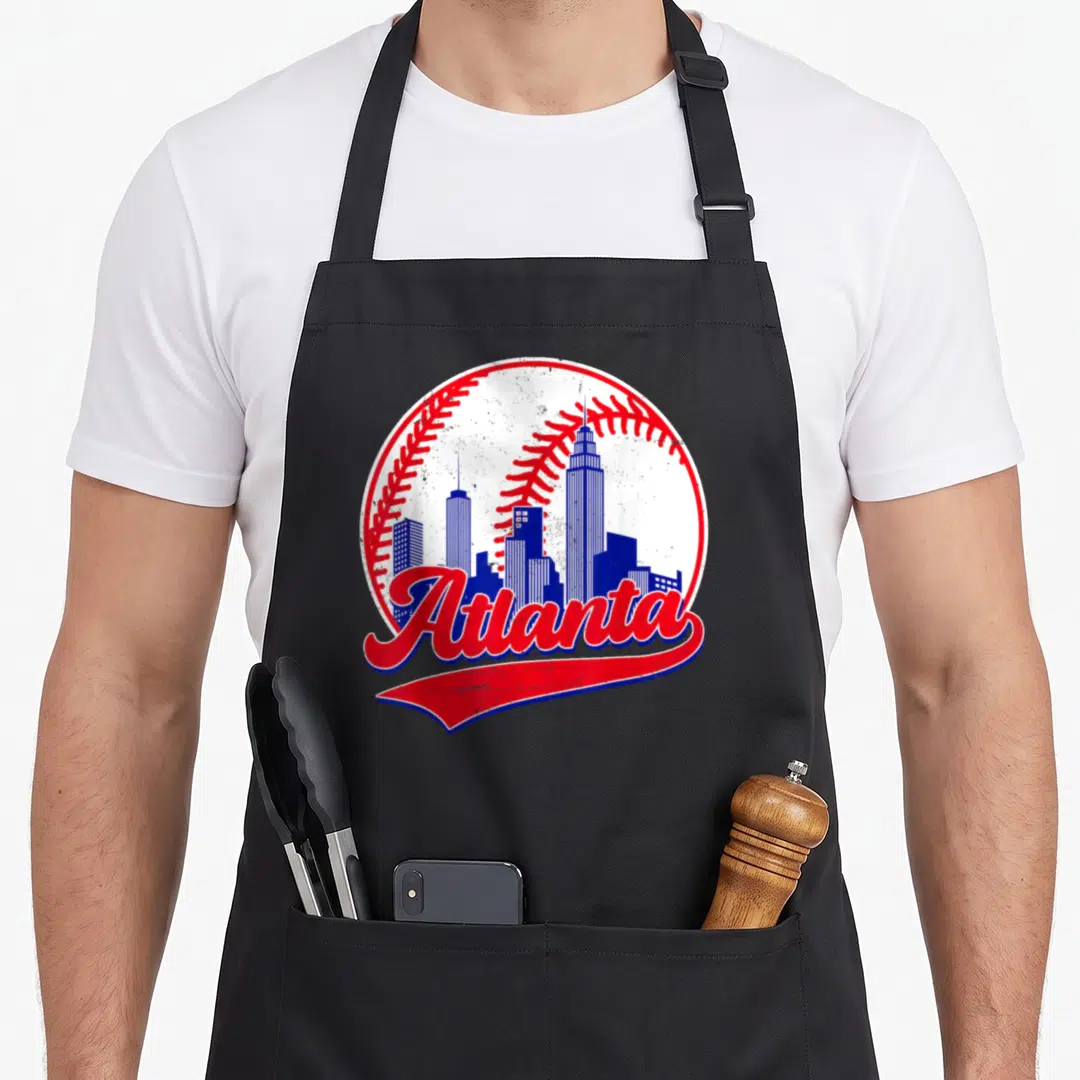Player atlanta baseball apron - Retro blue skyline inside white baseball with red stitching and Atlanta script — shown on a black cotton canvas apron against a white background