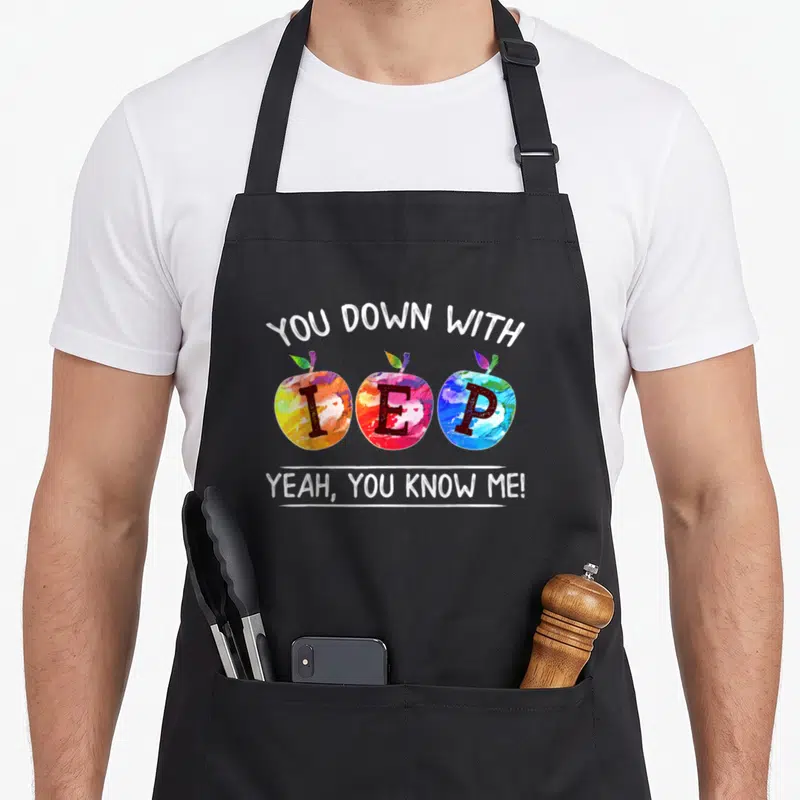 Yeah teacher apron - Three multicolor watercolor apples with IEP letters and You Down With IEP Yeah text — shown on a black cotton canvas apron against a white background