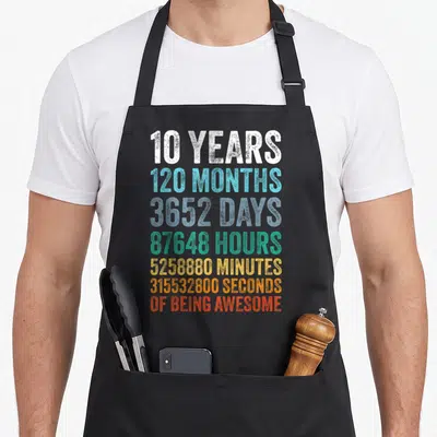 10yr dad and son aprons - Stacked text reading 10 Years 120 Months 3652 Days in white blue teal yellow orange and red — shown on a black cotton canvas apron against a white background
