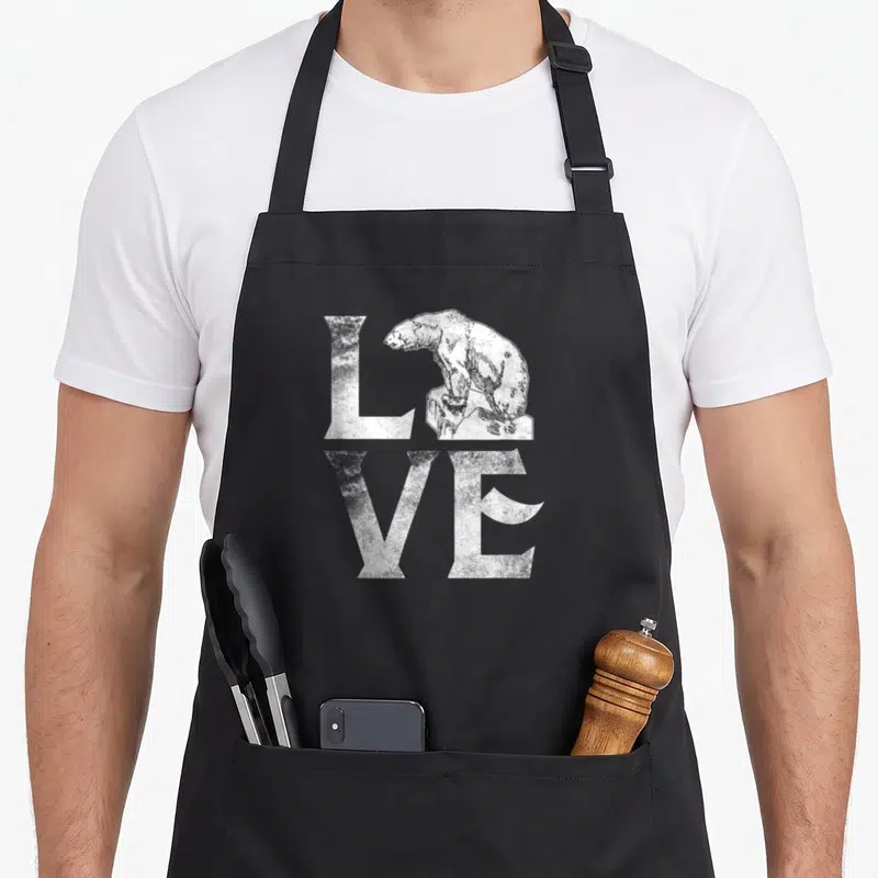 Polar change apron - Distressed white LOVE text with bear standing on rock replacing the O — shown on a black cotton canvas apron against a white background