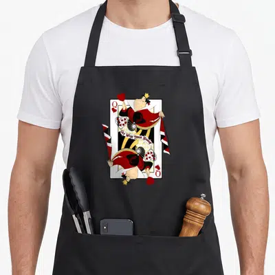 Wonderland queen apron - Mirrored Queen of Hearts playing card with Off With Their Heads text ribbon — shown on a black cotton canvas apron against a white background