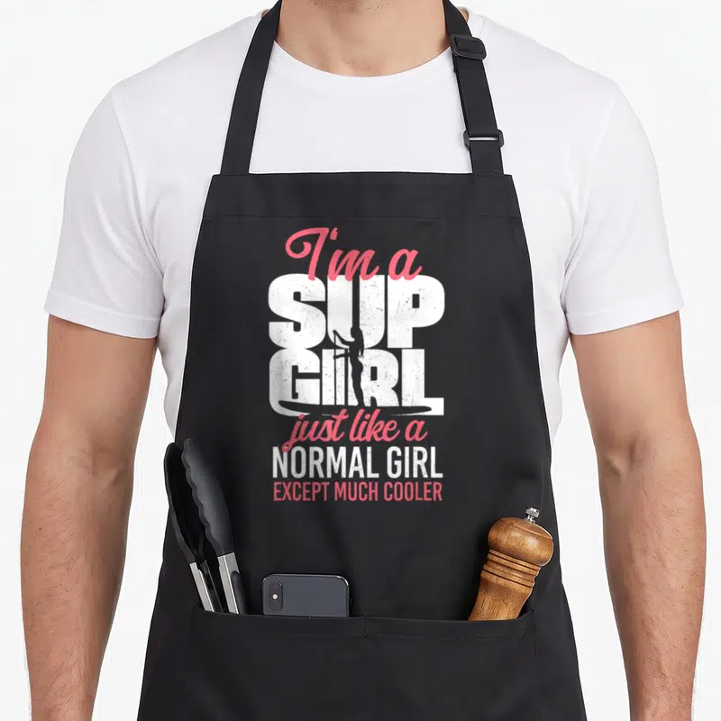 Normal paddleboard apron - I'm a SUP GIRL text with woman silhouette on paddleboard in white pink black — shown on a black cotton canvas apron against a white background
