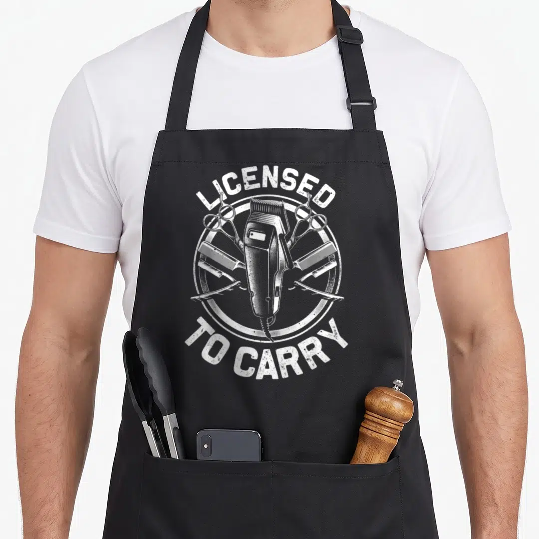 Stylist hairstyling apron - White distressed hair clipper and tools inside circle with arched text — shown on a black cotton canvas apron against a white background