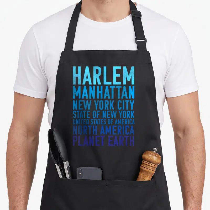Planet new york apron - Stacked text reading Harlem Manhattan New York City State USA North America Planet Earth — shown on a black cotton canvas apron against a white background