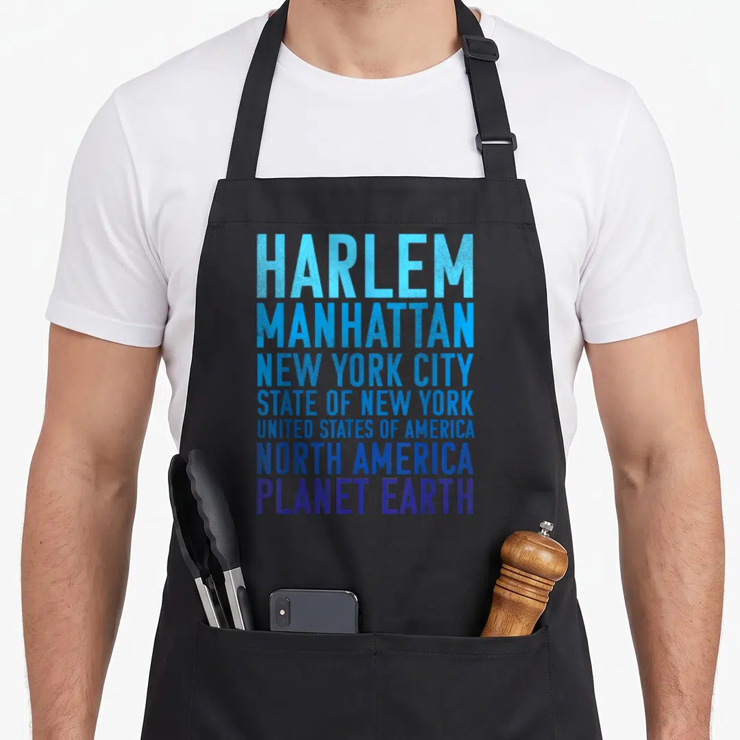 Planet new york apron - Stacked text reading Harlem Manhattan New York City State USA North America Planet Earth — shown on a black cotton canvas apron against a white background