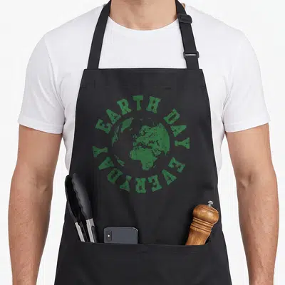 Environmental everyday apron - Green globe with arched EARTH DAY EVERYDAY text in minimalist circular layout — shown on a black cotton canvas apron against a white background