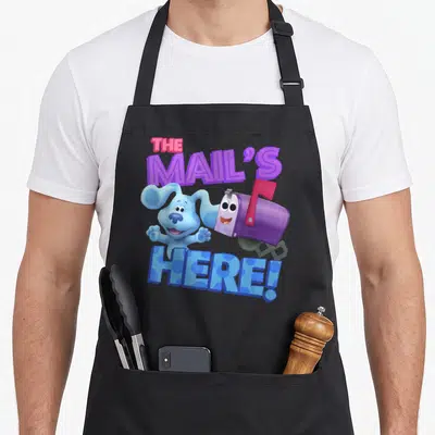 Mail clue apron - Blue dog and purple mailbox with THE MAIL'S HERE! text in cartoon style — shown on a black cotton canvas apron against a white background