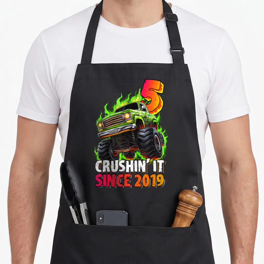 Monster 5th birthday truck apron - Green monster truck with flames and crushin it since 2019 text — shown on a black cotton canvas apron against a white background