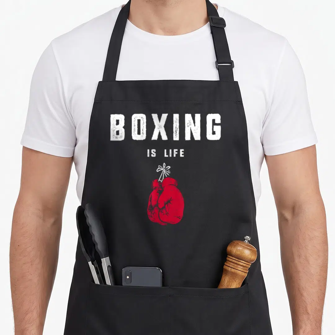 Cute boxing apron - Red boxing gloves tied with white string below stacked white distressed text reading BOXING IS LIFE — shown on a black cotton canvas apron against a white background