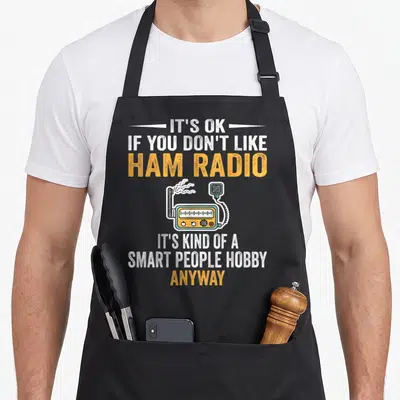 Hobby smart apron - Ham radio illustration with sarcastic white and orange text on a black background — shown on a black cotton canvas apron against a white background