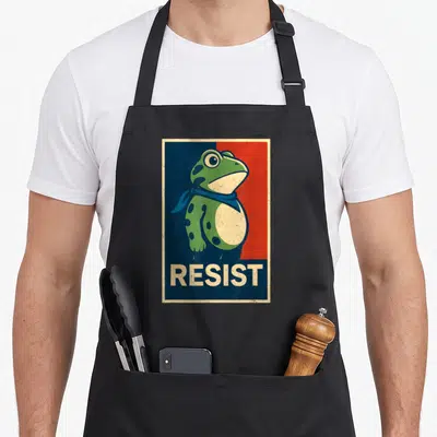 Portland frog aprons - Green frog in blue scarf against split blue red background with beige RESIST text bar — shown on a black cotton canvas apron against a white background
