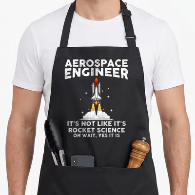 Aerospace engineer apron - Space shuttle launch graphic with Aerospace Engineer text and rocket science joke — shown on a black cotton canvas apron against a white background