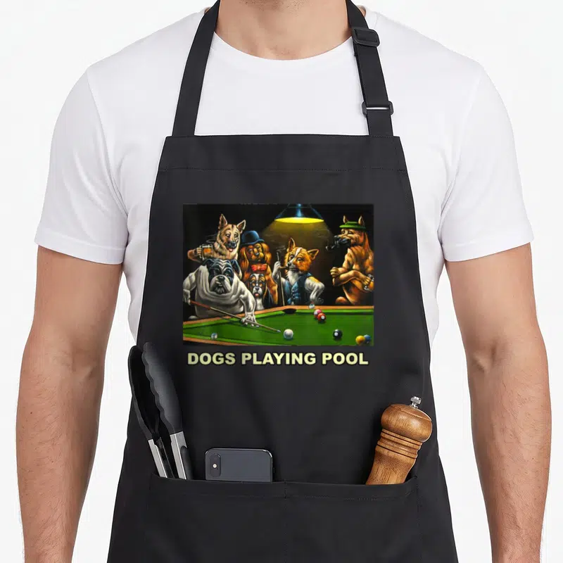 Pool dog apron - Realistic painting of dogs around a green pool table under a yellow lamp with text below — shown on a black cotton canvas apron against a white background