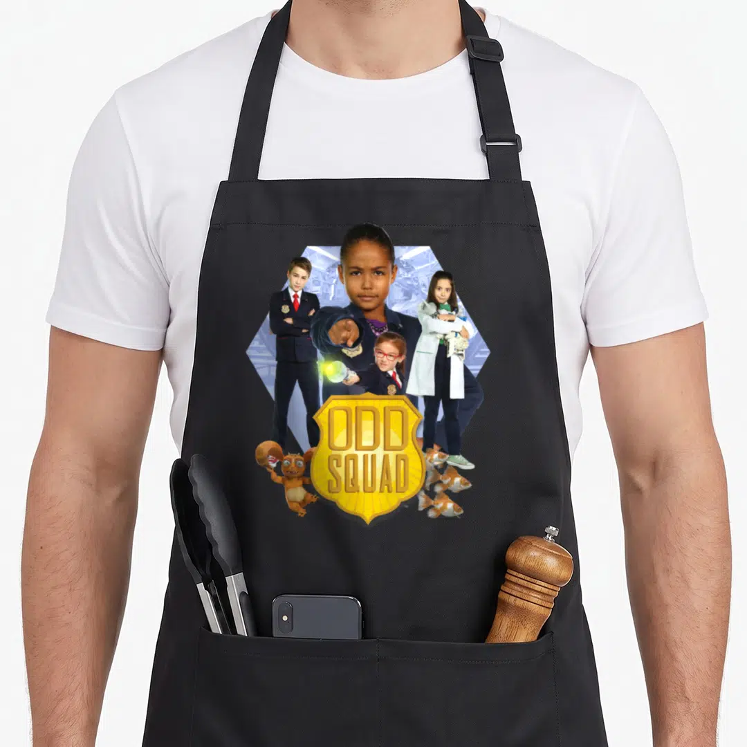 Odd online squad apron - Three people behind yellow badge with ODD SQUAD text, small creature, and three fish — shown on a black cotton canvas apron against a white background